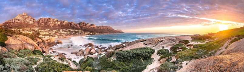 Breathtaking sunset panorama of the iconic Table Mountain and the Twelve Apostles range, Cape Town South Africa. A unique and scenic wide-angle perspective taken from Maidens cove