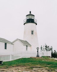Fototapeta na wymiar A white lighthouse with a white fence - Pemaquid Point Lighthouse in Bristol, Maine