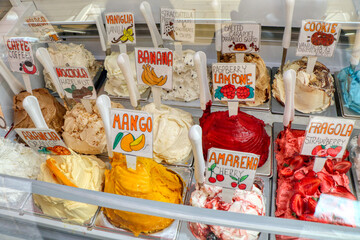 Various flavors of Italian fruit ice cream ready to be served to customers. Mango, strawberry, raspberry, banana, orange, hazelnut, vanilla, cherry, coffe