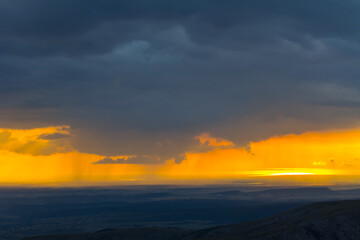 Fototapeta na wymiar mountain chain silhouette under dramatic cloudy sky at the twilight