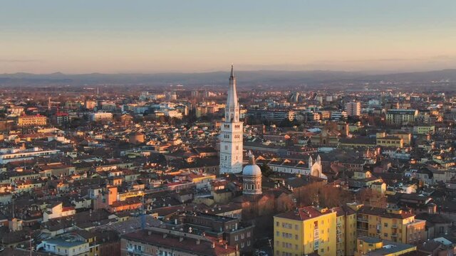 city of modena aerial view at sunset,drone flying backwards over downtown showing ghirlandina bell tower,emilia romagna italy 4k