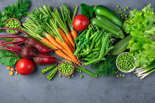 A large assortment of young vegetables and fresh herbs on a blue background. Top view, copy space.
