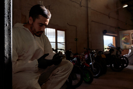 Male mechanic relaxing during break in workshop with motorbikes