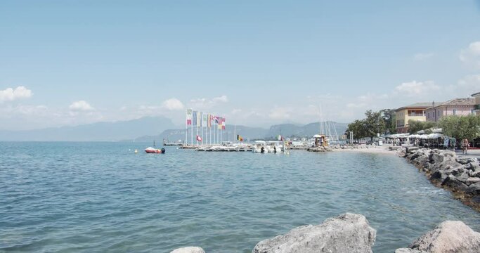 Cisano Port on Garda Lake, Bardolino. Harbour of Cisano near Lazise and Verona. Famous Porticciolo with tourists on bicycles and moored banks. Still shot and wide angle.