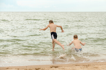 Two boys jump and dive into the sea water.