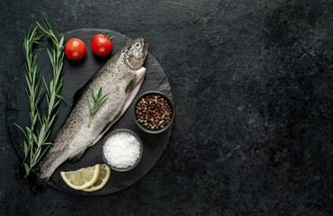 Obraz na płótnie Canvas raw fish trout with spices ready for cooking, on a stone background with copy space for your text