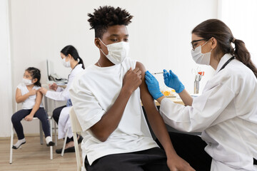 Obraz premium young male african wearing medical face mask and getting vaccinated from doctor, to build up or maintain immunity