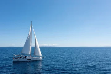  Sailing boat with open white sails, blue sky and rippled sea background © Rawf8