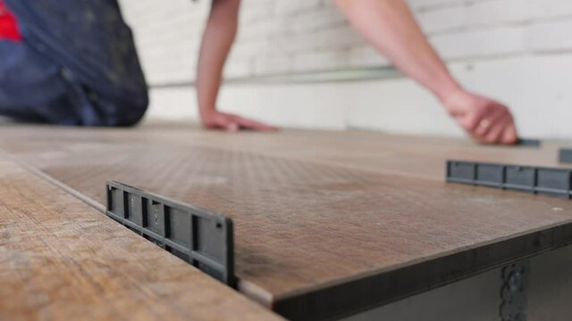 Carpenter sets spacing of deck boards on floor wood panel. Flooring installation work master builder construction home renovation building wood deck plank wooden floor covering. Repair home deck floor