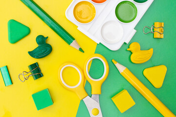 Bright yellow and green school accessories on green and yellow background. Back to school. Flat lay, top view