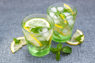 Two glasses of fresh lemonade drink or mojito cocktail on gray