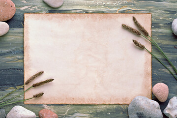 Minimal mockup, aged parchment with copy-space, wild grass and natural stones. Simple flat lay on...