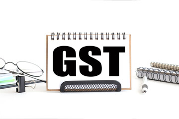 Acronym GST as Goods and Services Tax. Business and management concept. text on notepad. on a white background near the stationery