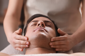 Obraz na płótnie Canvas Man receiving facial massage in beauty salon, closeup