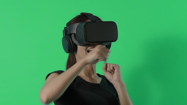 VR game playing. Asian teenager woman playing virtual reality game by VR headset. Blue or green screen background for chroma key. Playing game with happiness and excited. Cyber gaming World. 