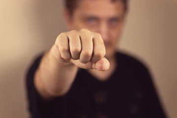 The hand is clenched into a fist for a blow, The concept of demonstrating aggression, fighting posture. Close-up, selective focus, blur.