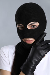 Woman wearing knitted balaclava on grey background