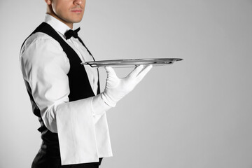Butler with tray on light grey background, closeup. Space for text