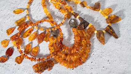 Many of different orange and yellow Baltic amber necklaces on a gray background. Ancient Slavic culture, amulet, talisman, handmade amber jewelry.  Flay lat. 