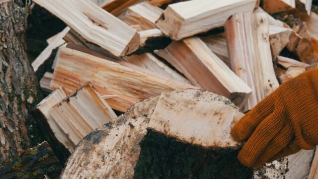 Man woodcutter chops tree trunks with an ax for firewood close up view
