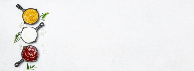 Set of tasty sauces on white marble background long banner format.