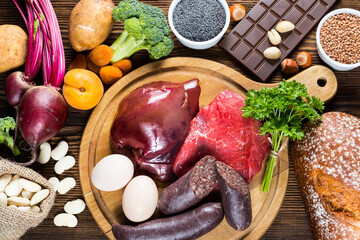 Collection iron rich foods as liver, beef, blood sausage, eggs, rye bread, dark chocolate, parsley leaves, dried apricots, bean, blue poppy seed, broccoli, beetroot, potatoes, nuts and pistachios. 