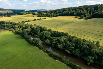 Obraz premium The landscape of the Werra Valley with the Werra River and agriculture fields at Herleshausen in Hesse and Thuringia