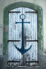 a vertical shot of white old door with blue anchor painting © lo-chef