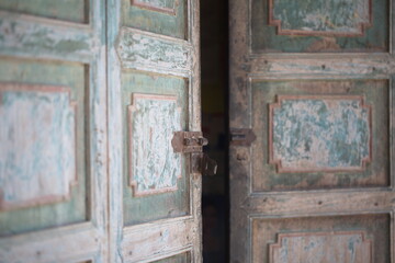 Old paint faded wooden door half open with lock in focus.