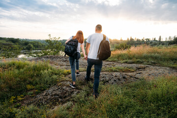 Fototapeta na wymiar Adventure, Hiking, Trekking, Bushcraft Concept. Solo family travel. Local travel. Young happy couple travelers hiking with backpacks on rocky trail on sunset evening.