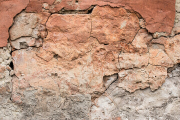 Destroyed old clay wall, abstract brown background. Cracked grunge surface, texture. Damage of facade building. Danger of collapse. Architectural design.