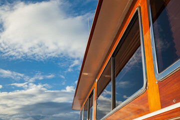 Wooden hull of a yacht with rectangular portholes against the sky, side view.