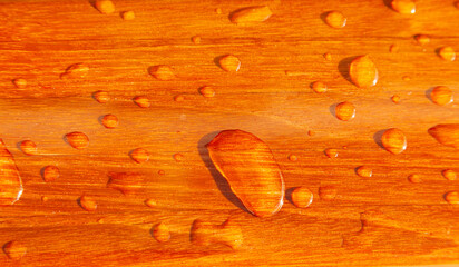 Raindrops on an orange wooden surface.