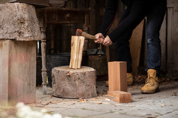 A lumberjack splitting logs of wood with an old axe on a big wooden stump to use for his fire wood stove while being self sufficient and living the simple life