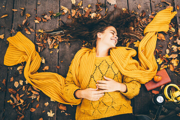 Young beautiful woman lies on autumn foliage in the park.