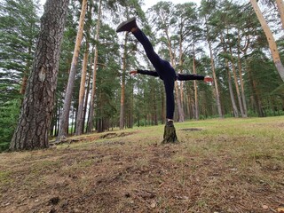 A young man is exercising in the forest. Warming up and stretching the muscles.