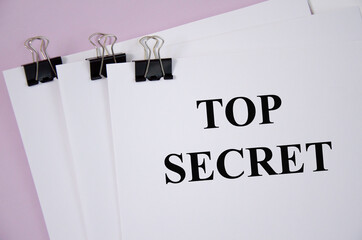 Top Secret concept written on white piece of paper and pink background. text