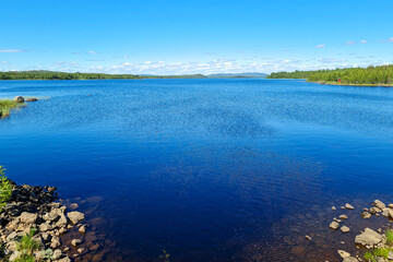 travel sweden and scandinavia, beautiful lake covered with trees and blue sky and white clouds above
