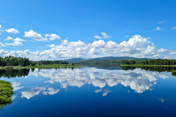 travel sweden and scandinavia, beautiful lake covered with trees and blue sky and white clouds above