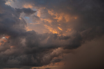 a dark thundercloud on the background of sunset