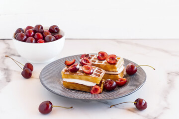 homemade belgin waffles whith whipped cream and cherries served on a plate for breakfast
