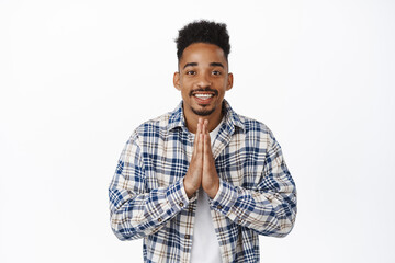 Thankful african american guy, showing namaste, beg gesture and smiling happy, appreciate opportunity, express gratitude, standing pleased against white background