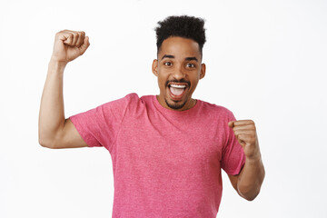 Fototapeta premium Portrait of excited african american guy chanting, sport fan cheering, rooting for team, celebrating victory, triumphing of score, standing against white background