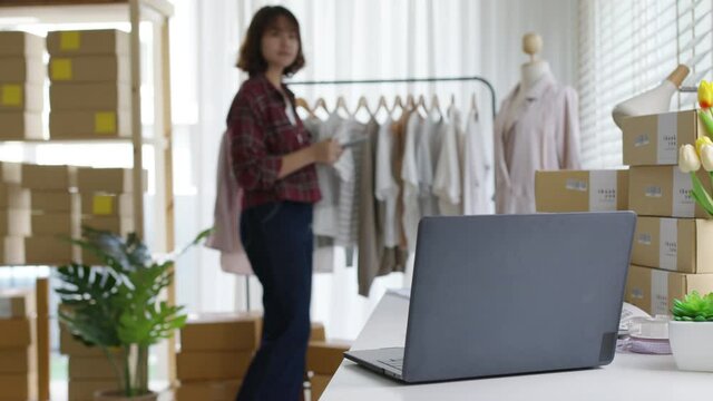 Digital tablet computer or laptop on home office desk with asia freelance seller woman happy packing check busy work in fashion studio SME online store social e-commerce sale page service web support.