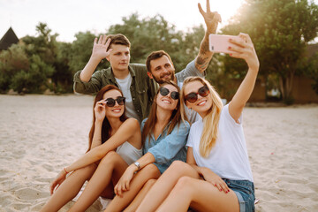 Selfie time. Group of friends taking selfie with the phone. Young friends enjoy summer party together at the beach. Friendship and lifestyle concepts.