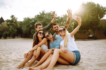 Selfie time. Group of friends taking selfie with the phone. Young friends enjoy summer party together at the beach. Friendship and lifestyle concepts.