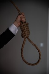 A businessman's hand is holding a noose of rope to hang. Suicide.
