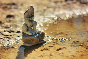 Teach A Man To Fish: a small zen sculpture or a Japanese man fishing in a puddle. 