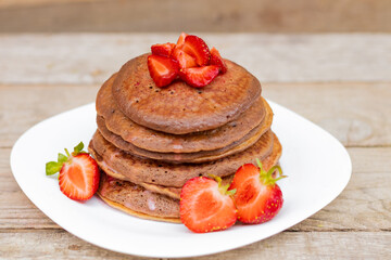 chocolate pancakes with strawberries, many, stack, on a white plate
