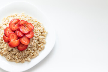 oatmeal with strawberries on a white plate, copy space